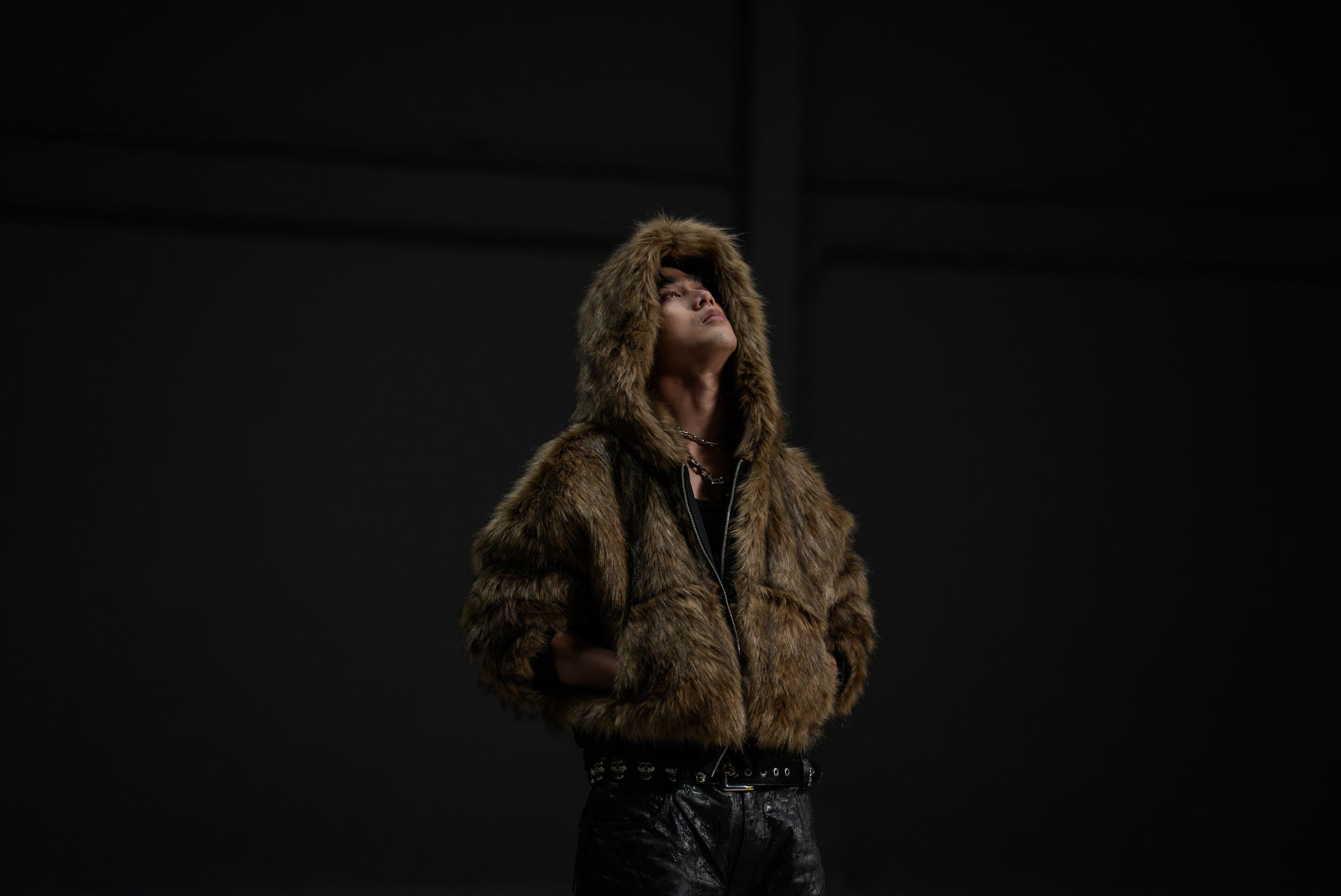 Josh Cullen in a fur hood, head tilted back, in a dark room